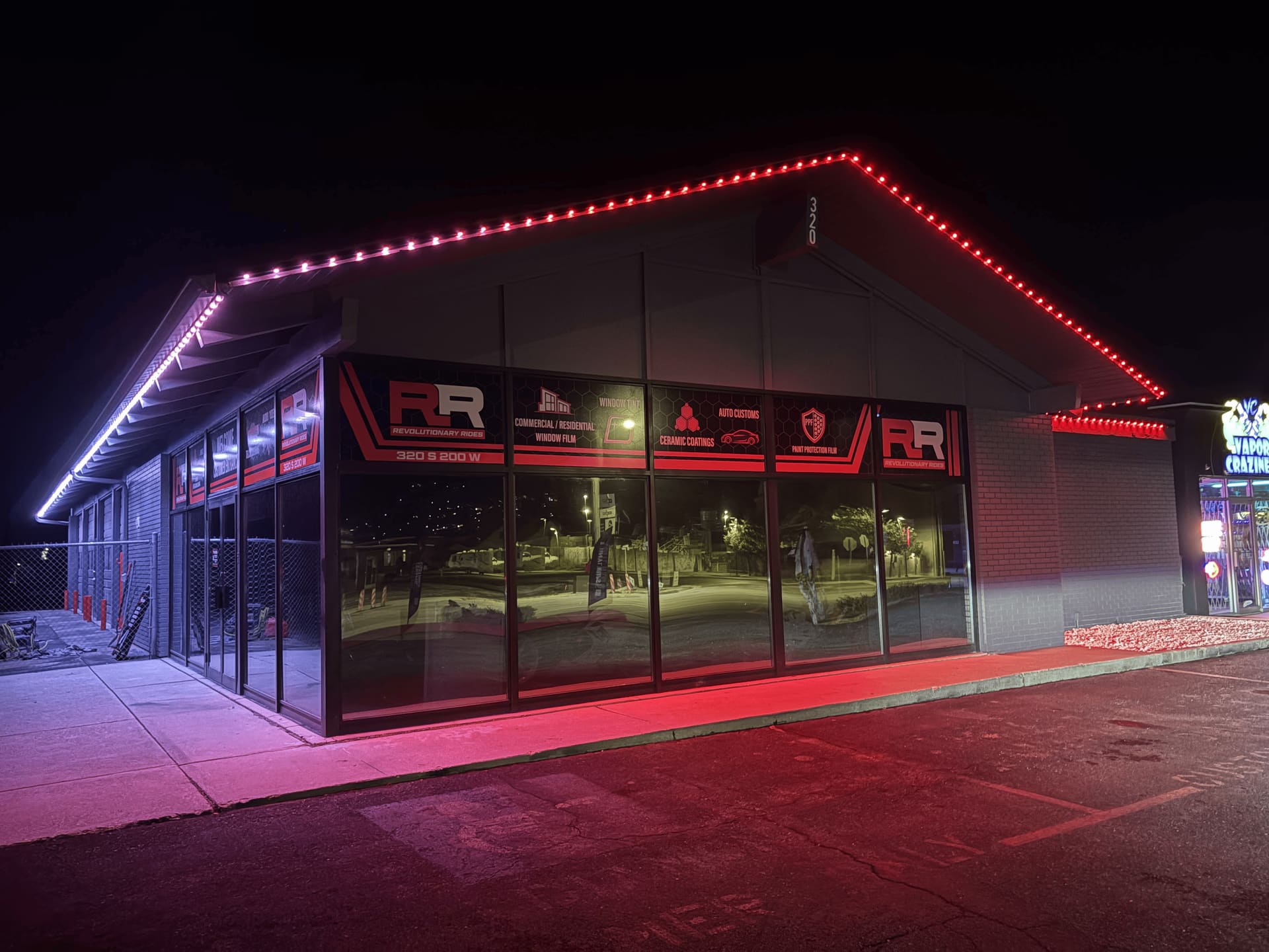 Revolutionary Rides building at night with vibrant red permanent lights outlining the entire roofline