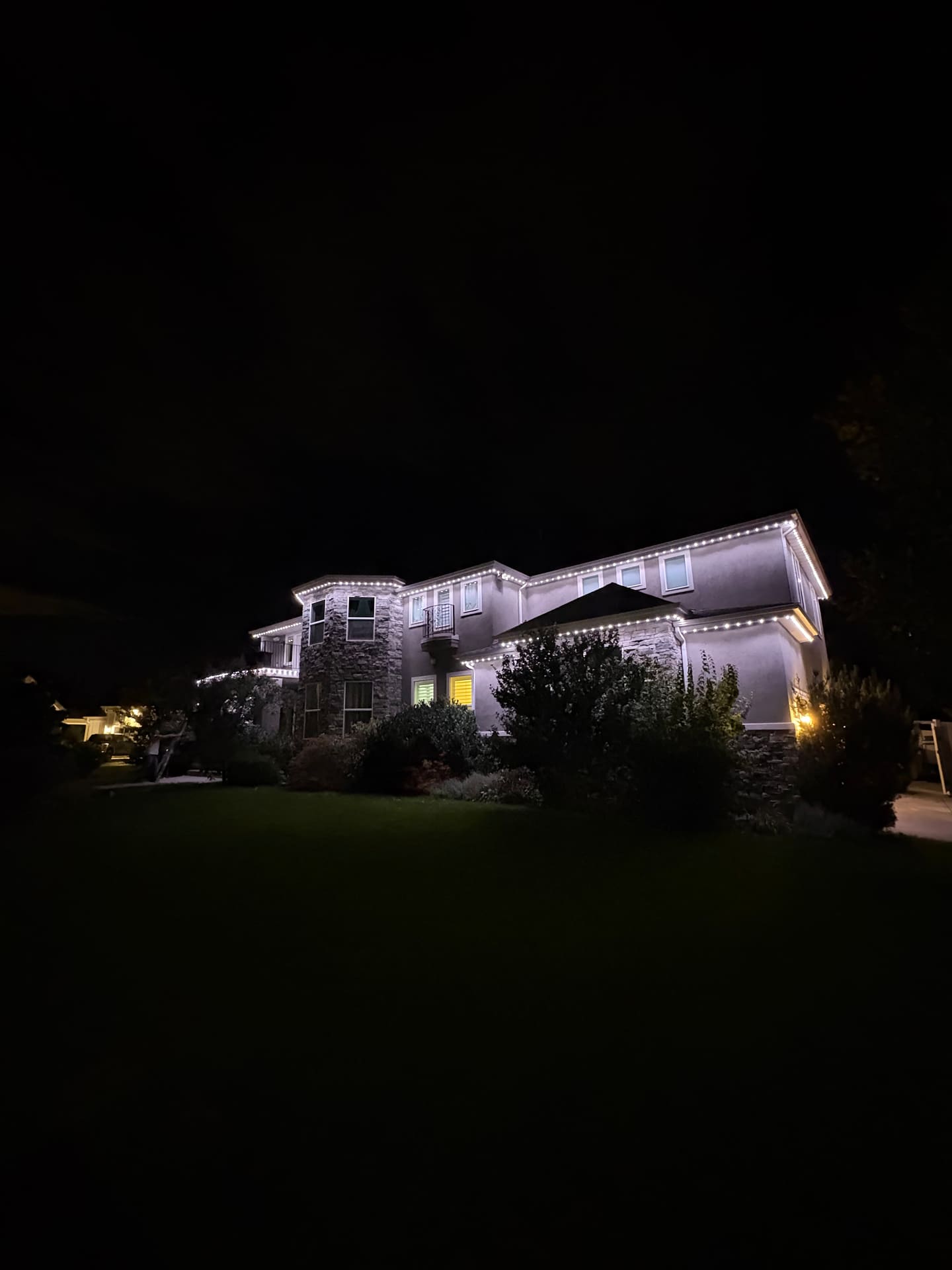 Stucco two-story home with warm white roofline lighting at night