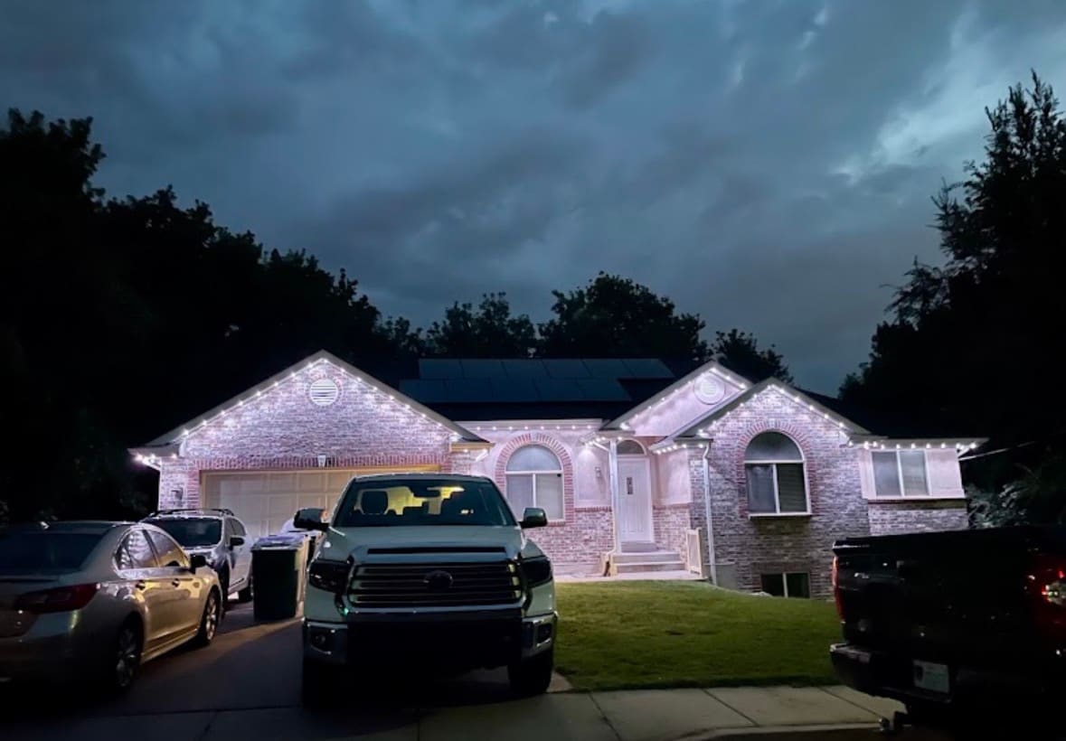 Brick rancher with warm white roofline and gable lighting at dusk
