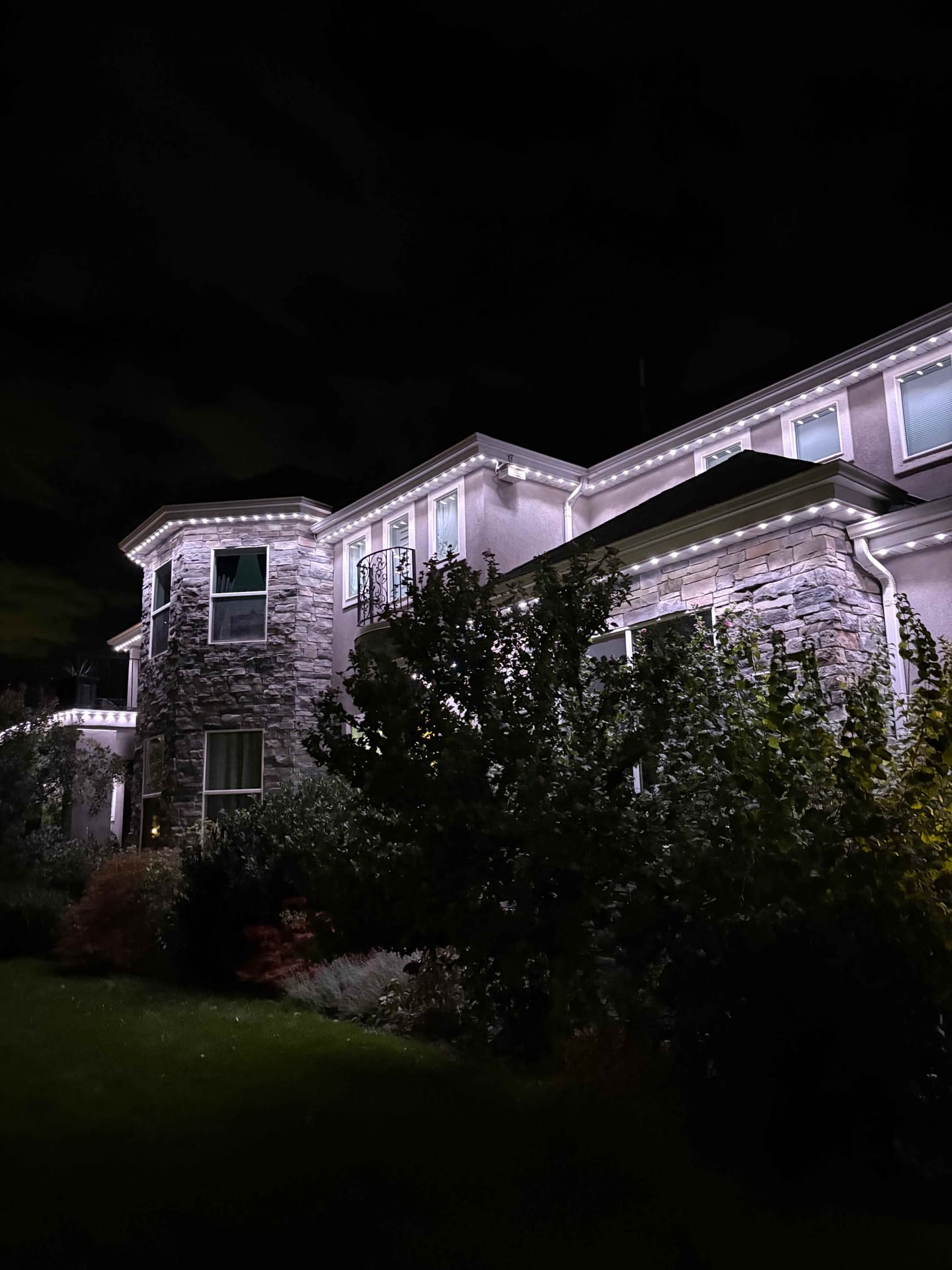 Large stone and stucco luxury home with clean warm white roofline and gable lighting