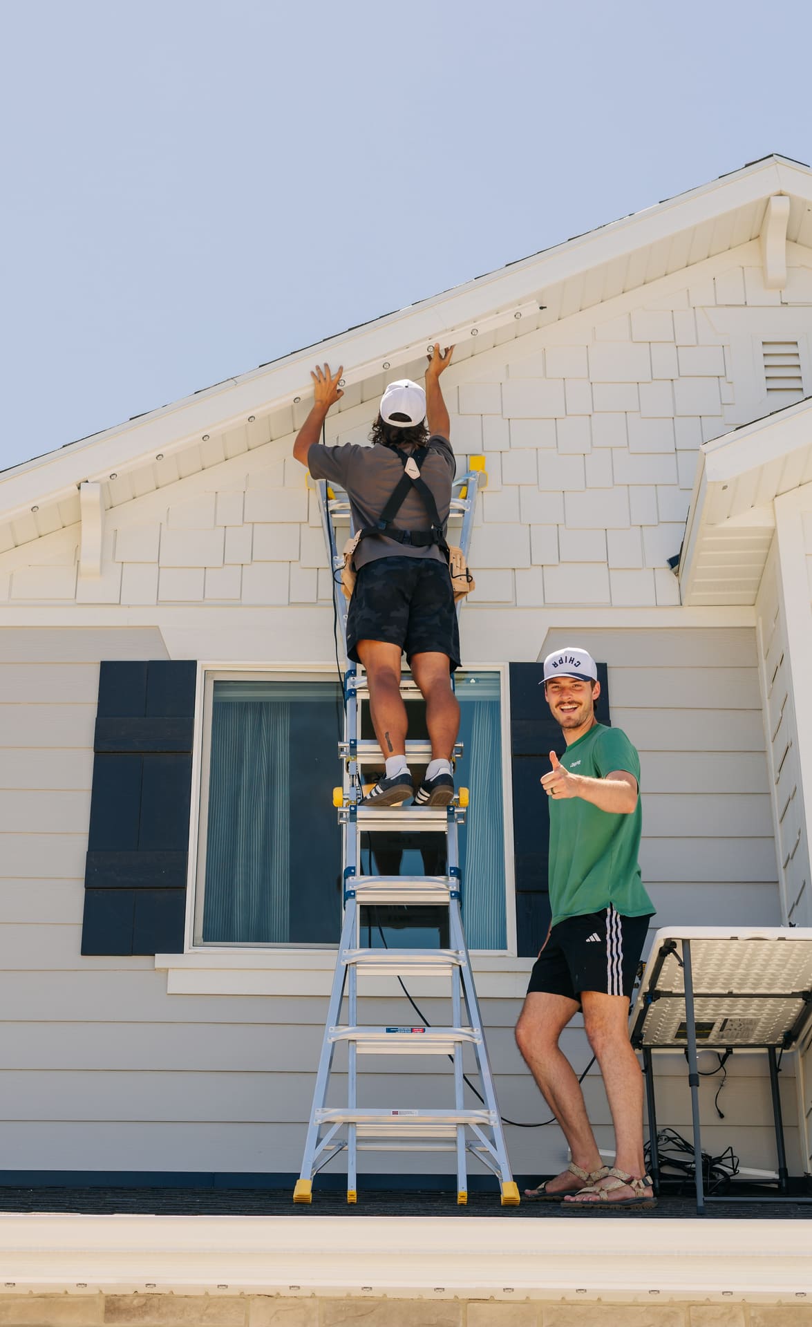 Two Chipr Lux installers fitting permanent lighting to a home